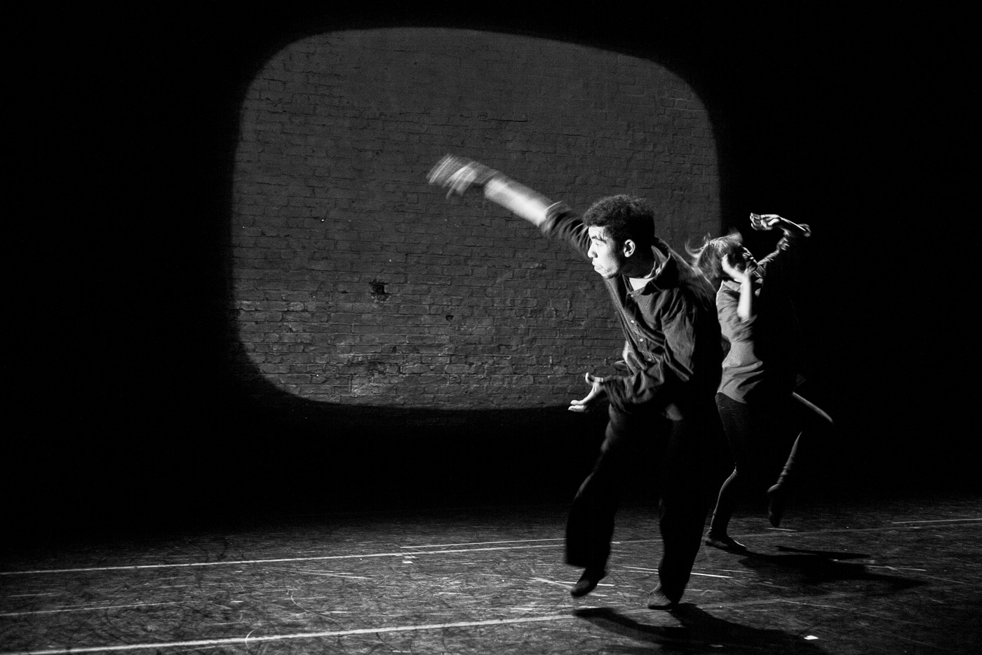 Black and white photo of DJ dancing with Eleanor Perry they are leaping energetically